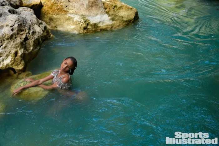 Lais Ribeiro wades in a pool of bright green water in a silver metallic top.